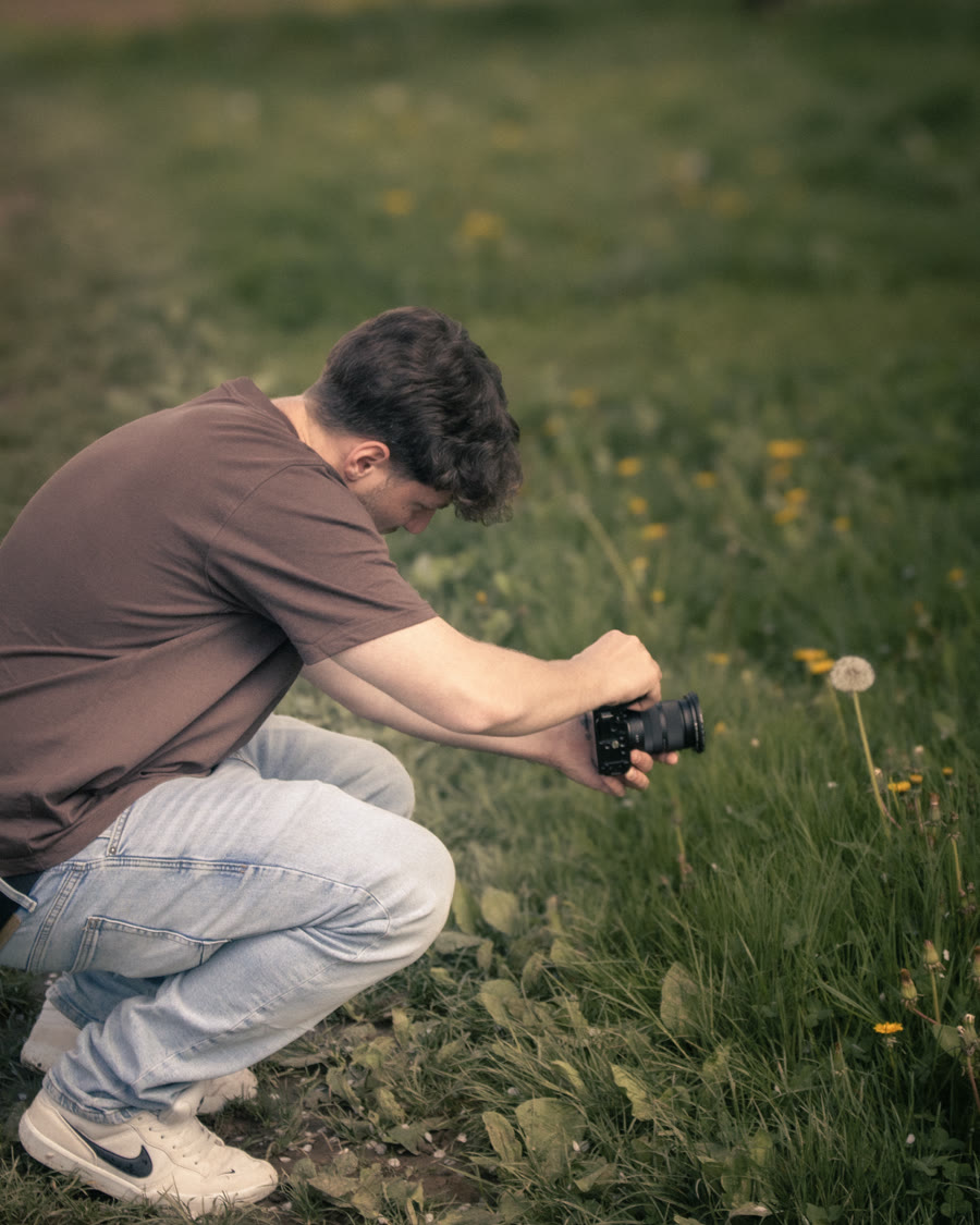 Michael Hetzel kniend beim Filmen auf einer Wiese